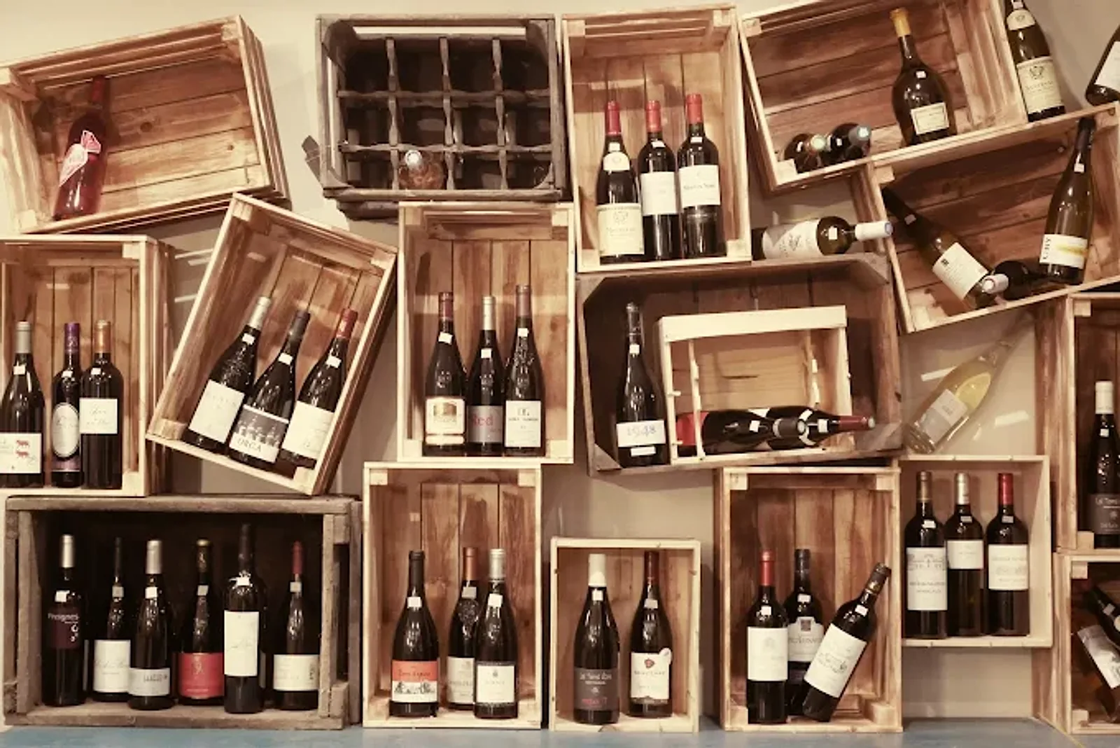 Mur de caisses en bois garnies de bouteilles de vin au bar à vins Les Sœurs Pinard à Lisieux