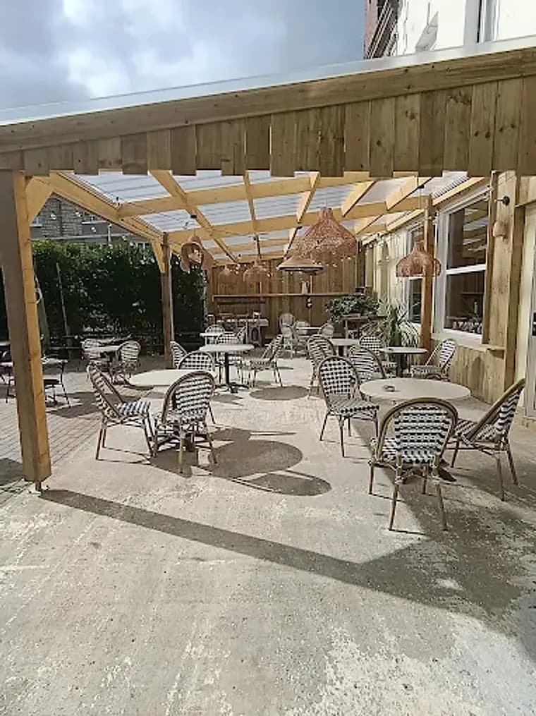 Terrasse couverte et arborée des Sœurs Pinard à Lisieux, un cadre intimiste pour déjeuner ou prendre un verre
